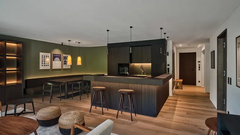 Modernes offenes Wohnzimmer mit integrierter Küche, Essbereich und Holzboden, ideal für geselliges Beisammensein.