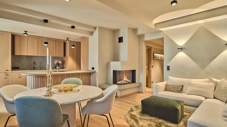 Offener Wohn- und Essbereich mit moderner Küche, Kamin und Holzboden, ideal für geselliges Beisammensein.