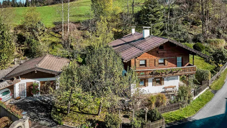 Traditionelles Haus im alpinen Stil mit Satteldach und grüner Umgebung in den Bergen.
