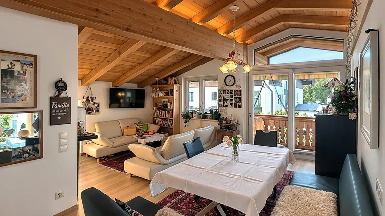 Geräumiger Wohn- und Essbereich mit Holzbalkendecke, Parkettboden und Zugang zum Balkon.