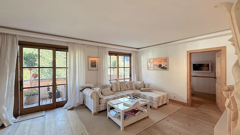 Helles Wohnzimmer mit gemütlichem Sofa, Holzboden und direktem Zugang zum Balkon.