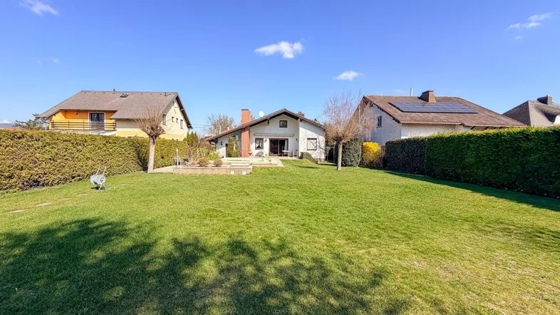 Großer, gepflegter Garten mit Rasenfläche, Hecken und Blick auf das Haus.