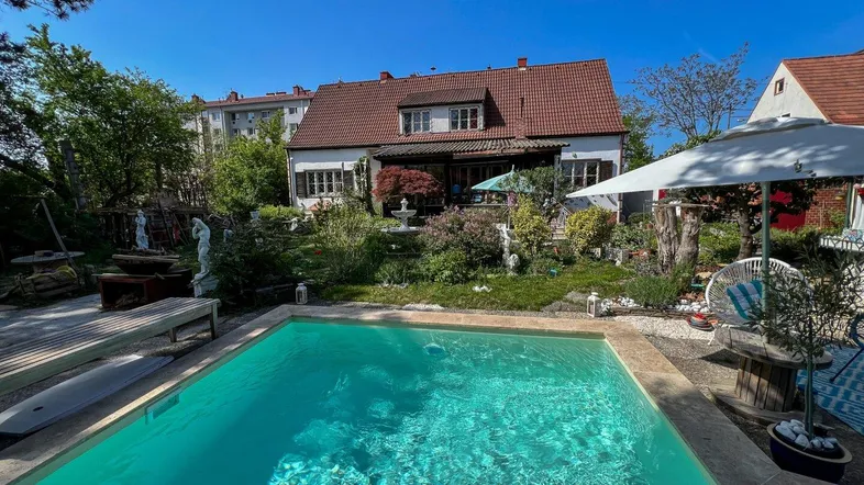 Großer Garten mit Swimmingpool, Liegebereich und üppiger Bepflanzung unter blauem Himmel.