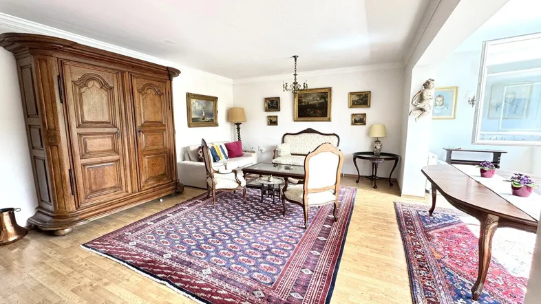 Geräumiges Wohnzimmer mit traditionellen Möbeln, Holzboden und einem großen Schrank.