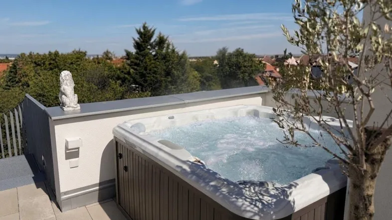 Großer Whirlpool auf der Dachterrasse mit weitem Blick über die Umgebung und viel Grün.
