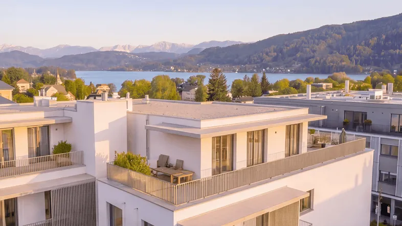 Moderne Wohnanlage mit Flachdächern, großzügigen Terrassen und Panoramablick auf See und Berge.