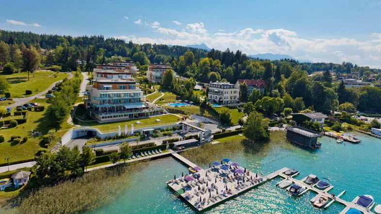 Luftaufnahme eines luxuriösen Anwesens am See mit mehreren Gebäuden, Steg und Liegeflächen.