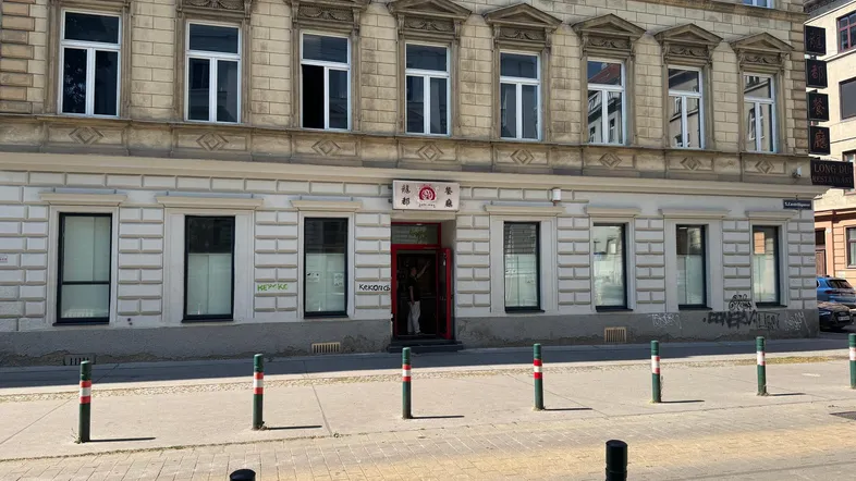 Historische Fassade eines Gebäudes mit großen Fenstern und einem Geschäftseingang im Erdgeschoss.