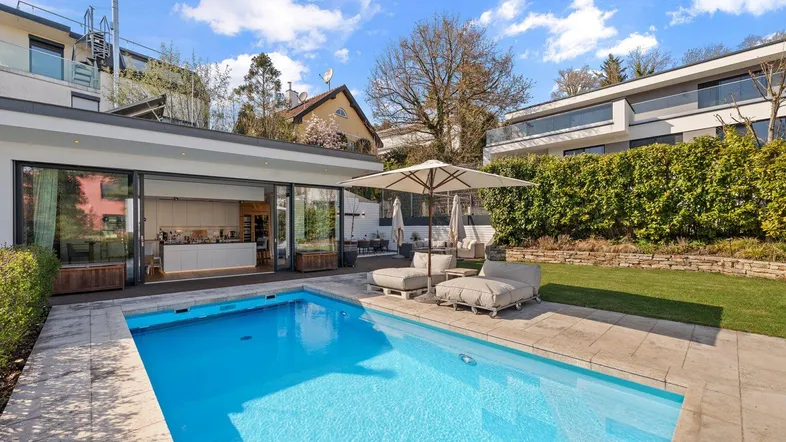Moderner Außenbereich mit großem Pool, Liegeflächen und direktem Zugang zur Küche.