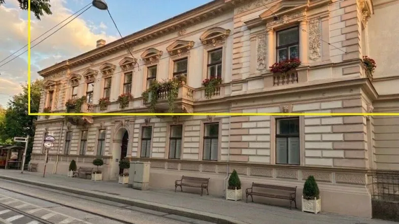 Elegantes historisches Gebäude mit aufwendiger Fassade und Balkonen an einer belebten Straße.