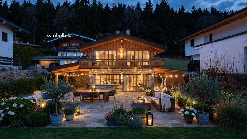 Charmantes Chalet mit großer möblierter Steinterrasse, umgeben von üppigem Grün und Wald.