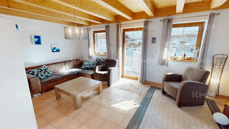 Helles Wohnzimmer im alpinen Stil mit Holzbalkendecke, Kamin und Zugang zur Terrasse.