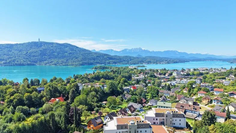 Panoramablick über eine Stadt am See mit umliegenden Bergen und Wohngebäuden.