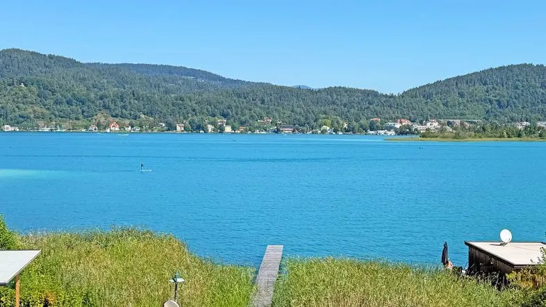 Atemberaubender Blick auf einen türkisfarbenen See mit bewaldeten Bergen und einem kleinen Steg im Vordergrund.
