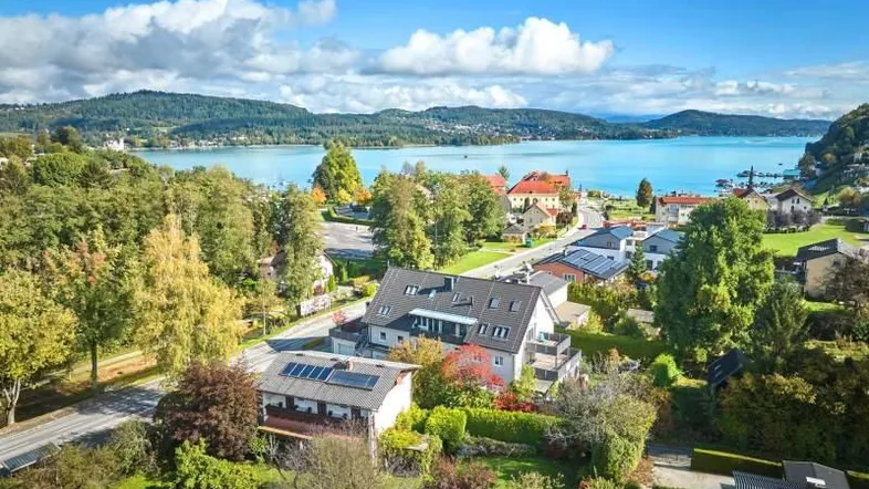 Luftaufnahme eines modernen Wohngebäudes mit Photovoltaikanlage und herrlichem Blick auf den See und die umliegende Landschaft.