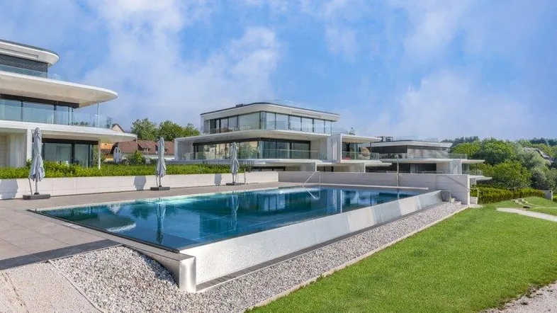 Moderne Wohnanlage mit großem Außenpool und luxuriösen Terrassenbereichen unter blauem Himmel.