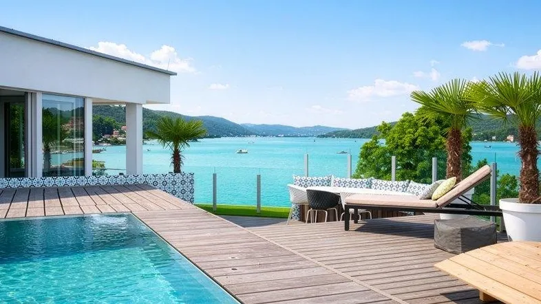 Moderne Terrasse mit Infinity-Pool, Holzdeck, bequemen Loungemöbeln und atemberaubendem Seeblick.