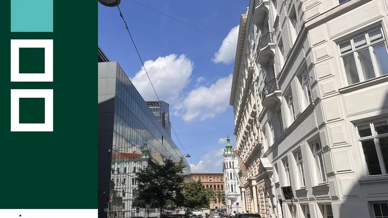 Blick auf eine belebte Stadtstraße mit historischen und modernen Gebäuden unter blauem Himmel.