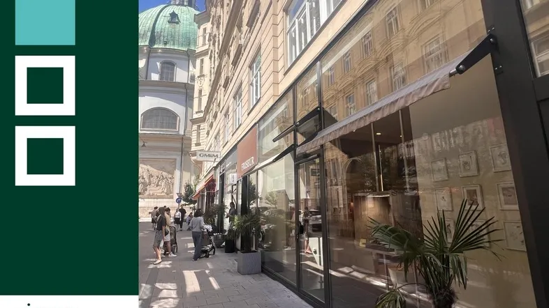 Außenansicht eines Geschäftsgebäudes in einer belebten Straße mit historischer Architektur im Hintergrund.