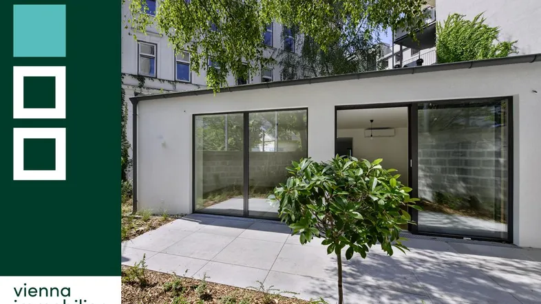 Moderne Terrassenfläche mit Zugang zu einem hellen Raum und umgebender Grünfläche, ideal für Entspannung im Freien.