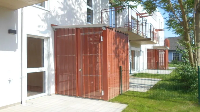 Außenansicht eines modernen Wohngebäudes mit Terrassen, Balkonen und grüner Rasenfläche.