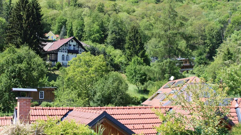 Malerische Aussicht auf grüne Hügel und traditionelle Häuser mit roten Ziegeldächern.