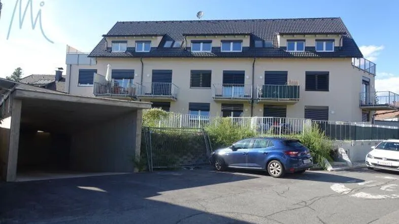 Mehrfamilienhaus mit moderner Architektur, Balkonen, Carport und Außenstellplätzen.