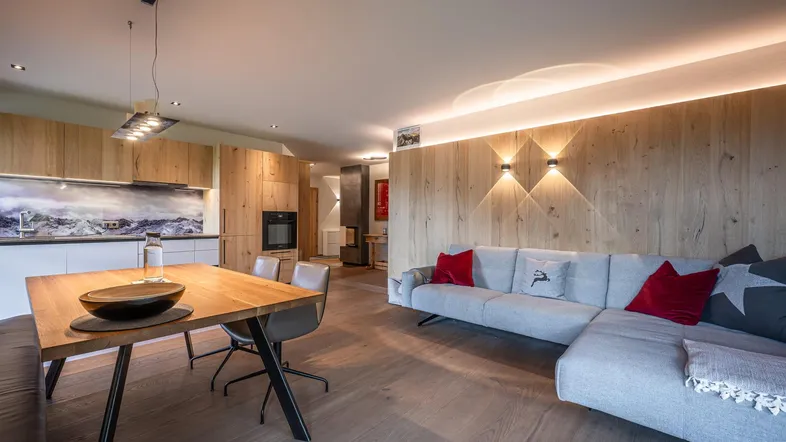 Moderner offener Wohn-Essbereich mit integrierter Holzküche und gemütlichem Sofa.