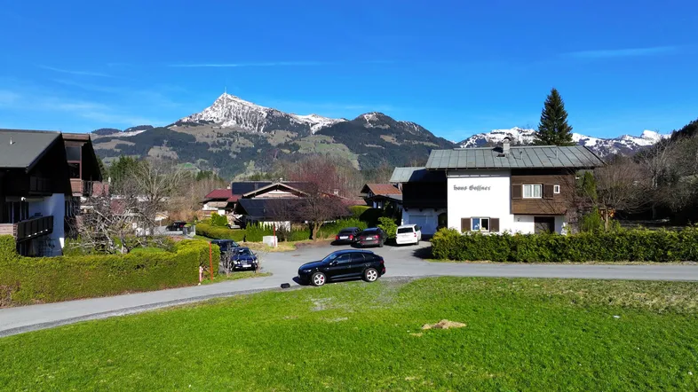Blick auf das Haus Gassner mit umliegender Landschaft und schneebedeckten Bergen im Hintergrund.