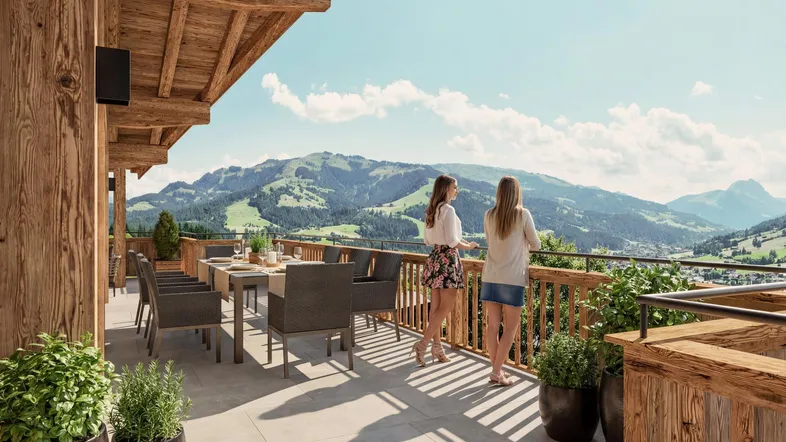 Geräumige Terrasse im Chalet-Stil mit Esstisch und atemberaubendem Bergblick unter blauem Himmel.