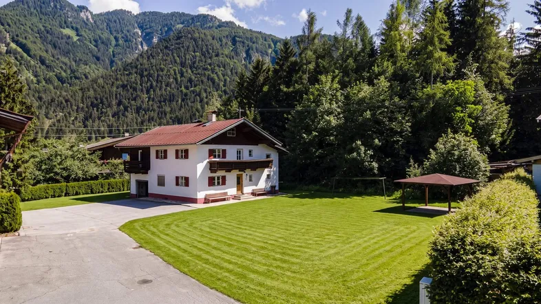 Charmantes Haus mit großem gepflegten Rasen und beeindruckendem Bergblick in sonniger Lage.
