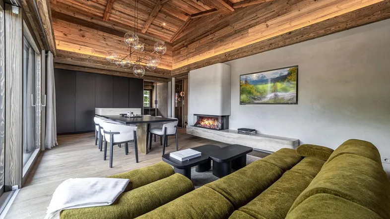 Geräumiger offener Wohn- und Essbereich mit Holzbalkendecke, modernem Kamin und gemütlichem Sofa.