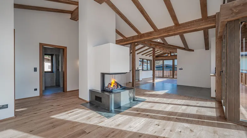 Heller Wohnbereich mit Holzbalken, Kamin und Eichenparkettboden, der viel natürliches Licht empfängt.
