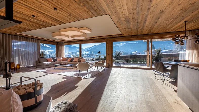 Großzügiges Wohnzimmer mit Holzboden und -decke, bodentiefen Fenstern und atemberaubendem Bergblick.