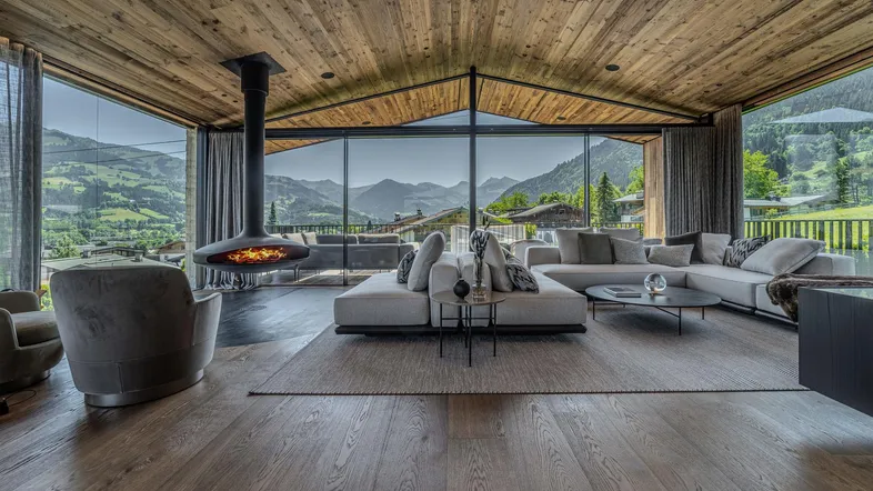 Luxuriöses Wohnzimmer mit atemberaubendem Bergblick, modernem Hängekamin und edlen Holzoberflächen.