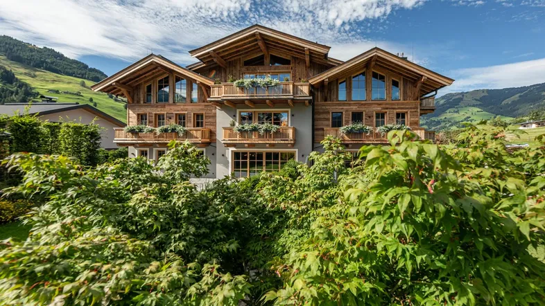 Beeindruckendes Chalet mit traditioneller Holzfassade und mehreren Balkonen vor alpiner Bergkulisse.