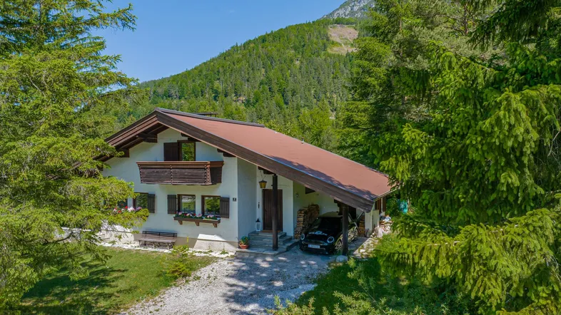 Charmantes Haus in alpiner Umgebung mit Bergblick und umgeben von grünen Bäumen.