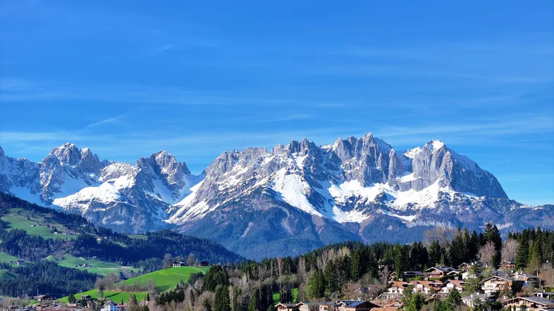 Panoramablick auf schneebedeckte Berge und ein malerisches Dorf in den Alpen.