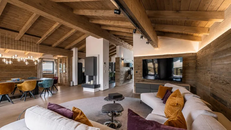 Geräumiger Wohn- und Essbereich mit Holzbalkendecke, modernem Kamin und stilvollen Möbeln.