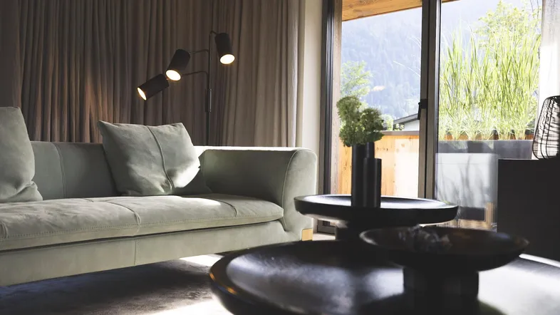 Helles Wohnzimmer mit modernem Sofa, Couchtisch und großen Schiebetüren zum Außenbereich mit viel Grün.