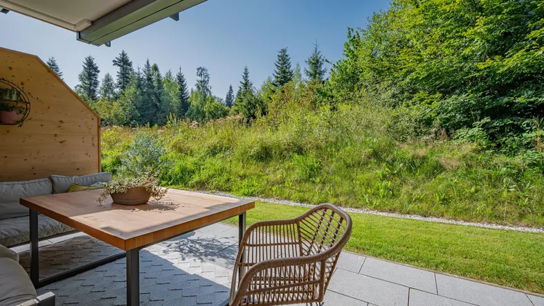 Gemütliche Terrasse mit Sitzgelegenheiten und weitem Blick ins Grüne, umgeben von Bäumen.