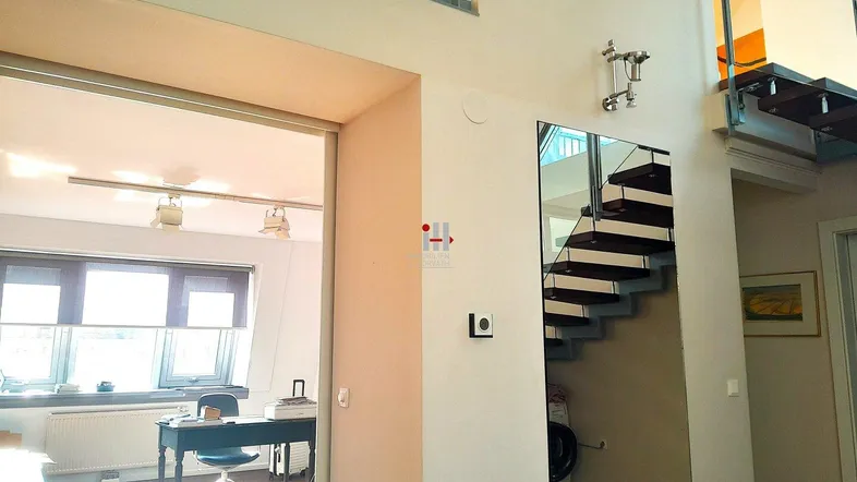 Heller, offener Wohnbereich mit moderner Treppe und Blick in ein Arbeitszimmer.