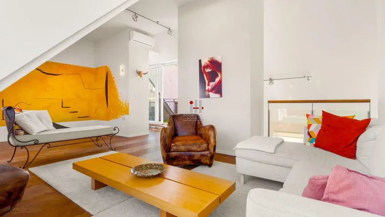 Helles Wohnzimmer mit Holzboden, moderner Einrichtung und farbenfroher Wandkunst.
