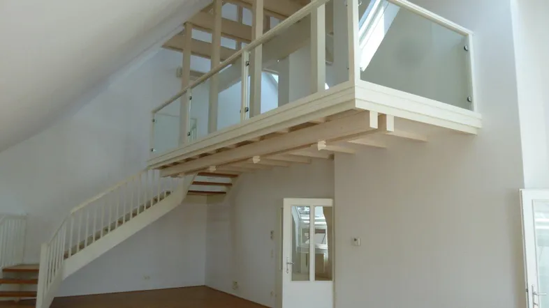 Helles Wohnzimmer mit offener Galerie, Holztreppe und hohen Decken.