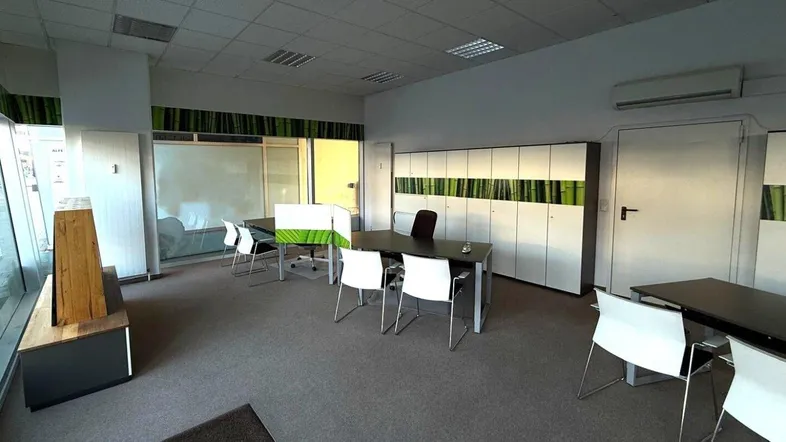 Großes, helles Büro mit mehreren Arbeitsplätzen, Teppichboden und großen Fenstern.