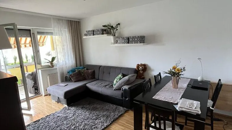 Heller Wohn- und Essbereich mit Sofa, Esstisch und Zugang zum Balkon.