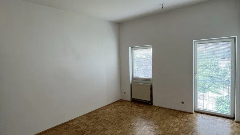 Helles Zimmer mit Parkettboden und Zugang zu einem Außenbereich, ideal für entspannte Stunden.