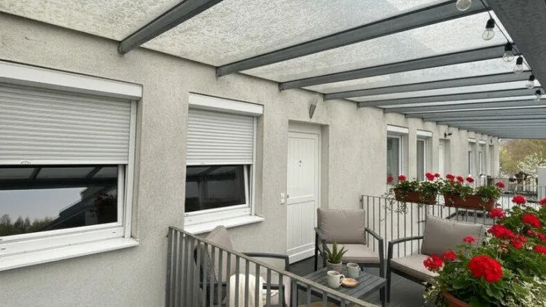 Überdachter Balkon mit Sitzgelegenheiten und Blumenkästen, ideal für entspannte Stunden im Freien.
