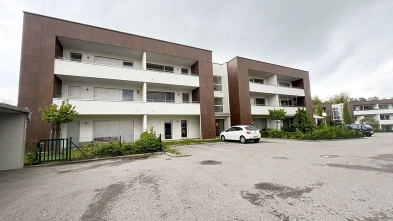 Modernes Mehrfamilienhaus mit Balkonen und ausreichend Parkplätzen vor dem Gebäude.