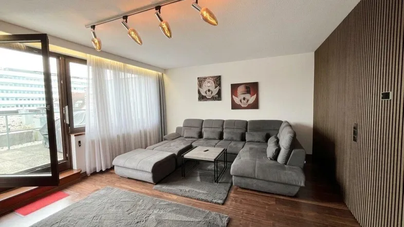 Helles Wohnzimmer mit großem Ecksofa, Holzboden und Zugang zu einem Außenbereich.